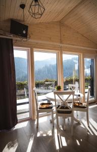 a dining room with a table and chairs and windows at Familyhata in Dzembronya