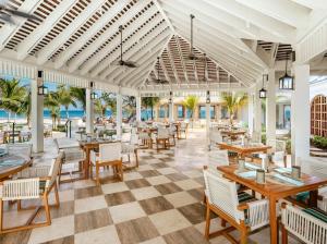 a restaurant with tables and chairs and the ocean at Half Moon in Montego Bay