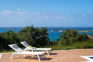 two white chairs and a table on a patio at Villa Aether Methoni in Methoni