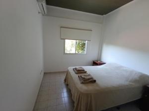 a white bedroom with a bed and a window at Numa Casa Temporal in Eldorado