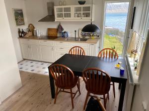 a kitchen with a black table and chairs and a window at Ocean view from front parquet in Oyndarfjørður