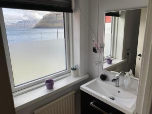a bathroom with a sink and a window at Ocean view from front parquet in Oyndarfjørður