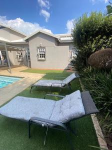 two empty benches sitting on the grass by a pool at Andisa Airport Escape in Kempton Park