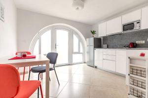 a kitchen with white cabinets and a table and chairs at Apartment Sweet Studio in Punat