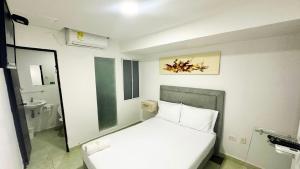 a small bedroom with a white bed and a bathroom at Hotel Casa Paraiso in Barranquilla