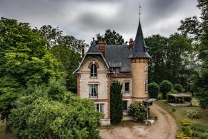 an old house with a turret in the trees at Le Cottage des chats in Beaulieu-sur-Loire