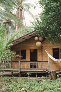a wooden house with a porch and palm trees at Casa Origen Nuqui in Coquí