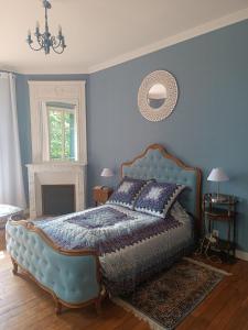 a bedroom with a bed with a blue wall at Le Cottage des chats in Beaulieu-sur-Loire