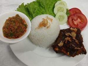 a plate of food with rice and meat and vegetables at Toba-A-Scape in Ambarita