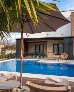 a pool with chairs and an umbrella next to a house at Luxury Villa Bar in Bar