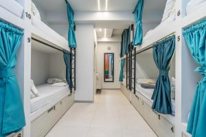 a corridor with three beds in a dorm room with blue curtains at BaruHaus GRUPOS Alea ALOJAMIENTO COMPLETO in León
