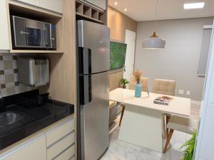 a kitchen with a stainless steel refrigerator and a table at Recanto das Colinas II in Espirito Santo Do Pinhal