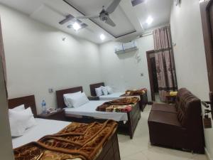 a hotel room with three beds and a couch at Second Home Hotel in Multan