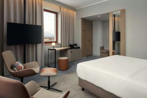 a hotel room with a bed and a desk and chairs at Courtyard by Marriott Pilsen in Pilsen
