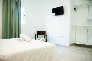 a white bedroom with a bed and a tv at Hostal España in Arrecife
