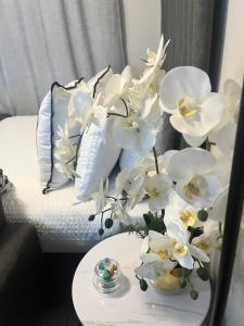 a vase of white flowers on a table next to a bed at B-Hive at Devland Room 3 in Soweto