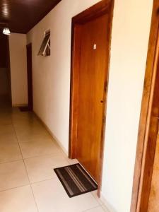 a hallway with a wooden door and a rug at Pousada Pinho Verde in Monte Verde