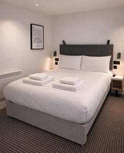 a bedroom with a large white bed with two pillows at Lidos Hotel in London