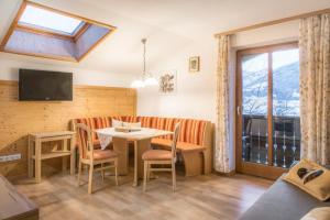 a living room with a table and chairs and a tv at Bauernhof Grussberggut GRATIS THERME & SOMMERBERGBAHN in Bad Hofgastein