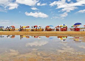 a group of people sitting under umbrellas on the beach at Riviera Sanary 1207 Nova Almeida in Serra