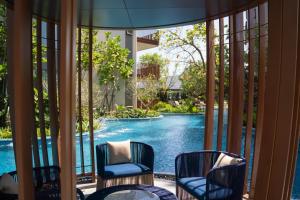 a view of a swimming pool from a room with chairs at Lovely 2 Bdr Canvas BangTao in Laguna Phuket