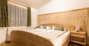 a bedroom with a wooden bed with a wooden headboard at Bauernhof Grussberggut GRATIS THERME & SOMMERBERGBAHN in Bad Hofgastein