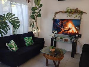 a living room with a black couch and a tv at Casa Monstera Bahia in Naranjo