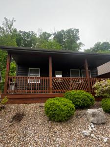 a house with a large deck with bushes in front at Papa Chubbys RV Resort in Sunrise Beach