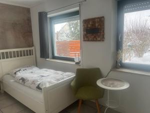 a bedroom with a bed and a chair and a window at Spitzenbergblick in Reichensachsen