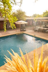 a swimming pool with a table and an umbrella at Hostel Qiru Atacama in Sólor +14 photos