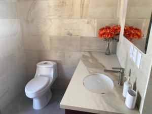 a bathroom with a toilet and a sink with flowers at Casa Kimara in Uvita +14 photos
