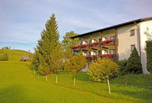 ein Haus auf einem Hügel mit Bäumen und einem Zaun in der Unterkunft Hotel Allgäu Garni in Scheidegg