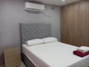 a small bedroom with a white bed and a fan at Gabriela House in Ríohacha