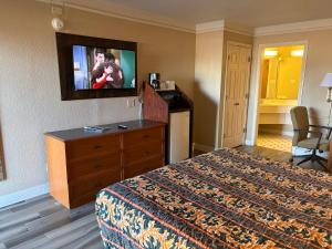 a hotel room with a bed and a flat screen tv at America's Inn Houston/Stafford /Sugarland in Houston +9 photos