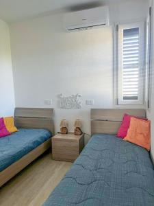a bedroom with two beds and a window at Smeralda Apartment - Golfo Aranci in Golfo Aranci