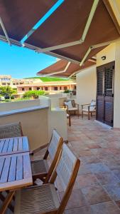 a patio with wooden tables and chairs on a balcony at Smeralda Apartment - Golfo Aranci in Golfo Aranci