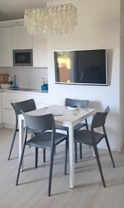 a white dining room table with chairs and a tv at Smeralda Apartment - Golfo Aranci in Golfo Aranci