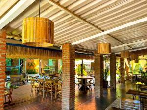 a dining room with tables and chairs and chandeliers at Casa das Flores Bistrô e Pousada in Taquarussu Tocantins