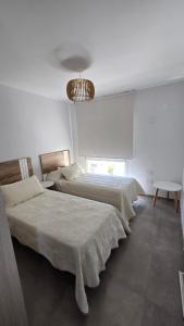 a bedroom with two beds and a chandelier at Departamento BARBÚ in Villa María
