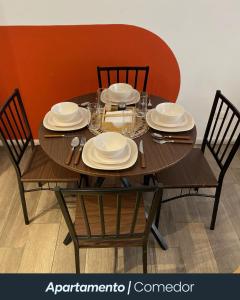 a wooden table with chairs and plates on it at Narama 1 - Apartamento cerca del aeropuerto - Zona 13 de la Ciudad de Guatemala in Estación Pamplona
