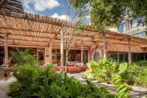 an outdoor patio with a wooden pergola at Moxy Tulum in Tulum