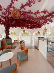 a room with tables and chairs and a tree with pink flowers at Santorini Transit hotel in Negombo