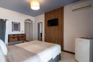a bedroom with a bed and a television in it at Pousada dos Gravatás in Búzios +108 photos