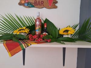 a table with two bottles and flowers on it at MAISON DE VACANCES KAZ A LOLO in Port-Louis