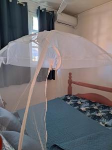 a bed with a white canopy in a bedroom at MAISON DE VACANCES KAZ A LOLO in Port-Louis