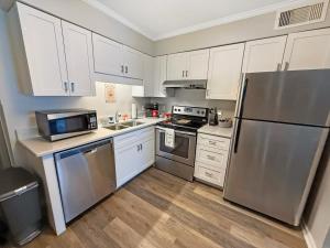 a kitchen with white cabinets and a stainless steel refrigerator at Portabella Paradise in Carolina Beach