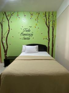 a bedroom with a bed with trees on the wall at Hotel MERLI in Asunción Nochixtlán