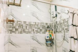 a bathroom with a shower with white marble tiles at Rubi's House in Ilayang Talim +70 photos
