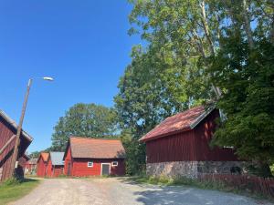 a red barn next to a dirt road at Cozy Smalandcottage Alsterfors 23 - towels, bed linen and toiletries provided - in Alsterfors