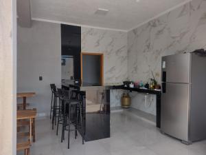 a kitchen with a bar with stools and a refrigerator at Área de Lazer Portal da Canastra in Delfinópolis